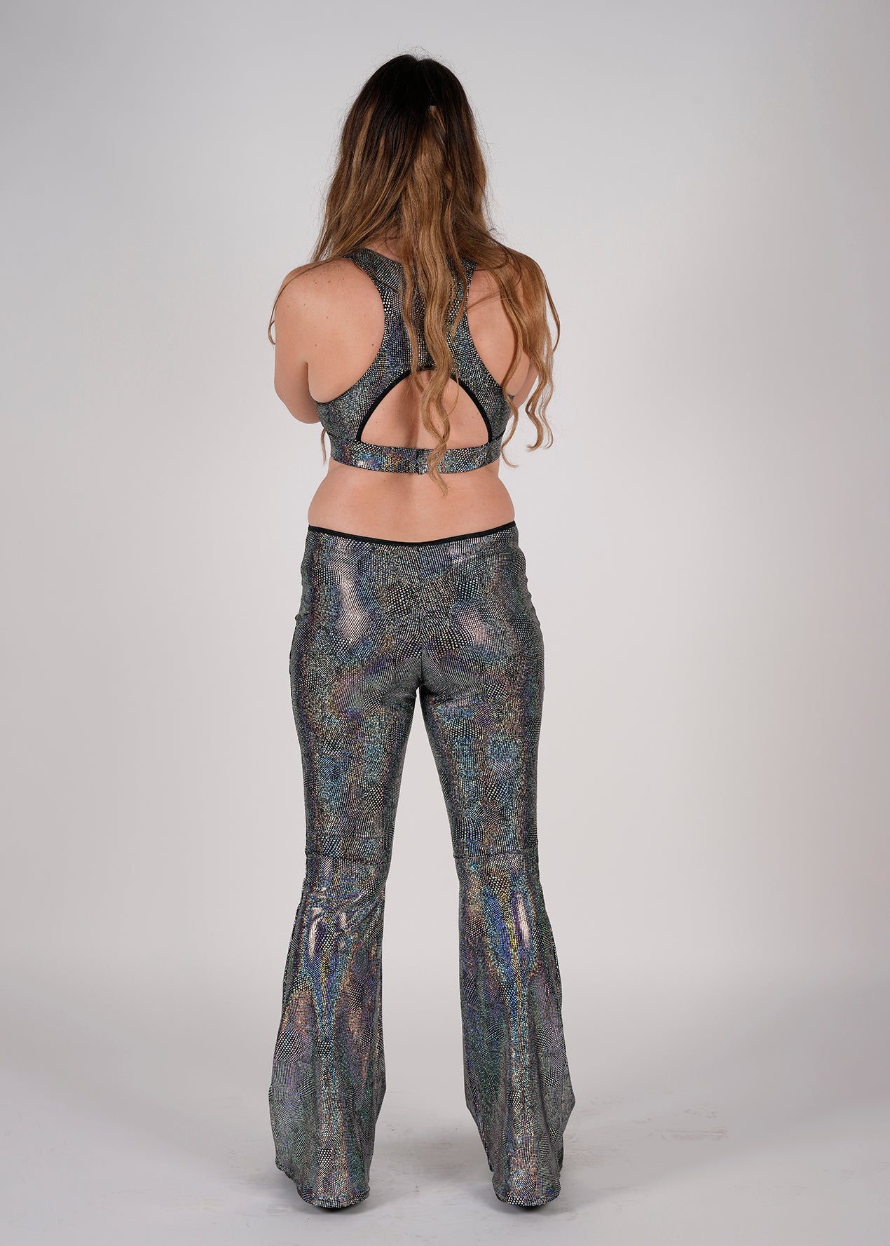 Unisex-music fesival fashion - Festival-outfit-rave-outfit - handmade-in-Brooklyn-New York City-custom made-waste conscious– retro style – hippie fashion –handmade –  Ready-Diva-One Jumpsuit – two-piece with clasp – versatile festival wear – racerback – bellbottoms - back view on model - mercury sparkle silver print